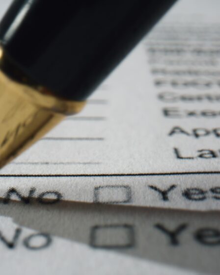 Closeup hand filling questionnaire on paper. Ballpoint writing marks on document