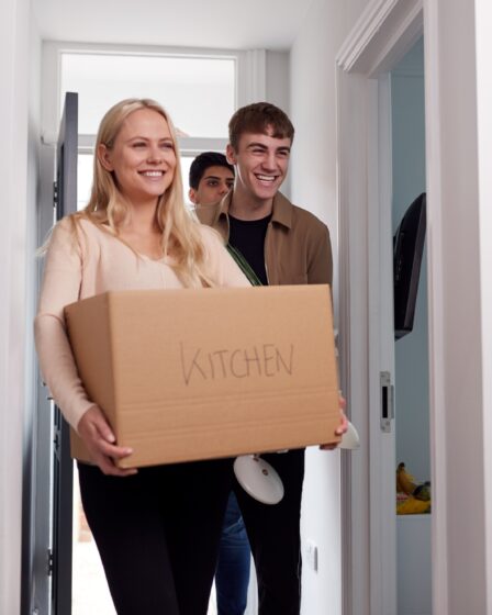 Group Of College Student Carrying Boxes Moving Into Accommodation Together