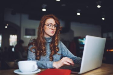 Thoughtful woman browsing laptop in cafe