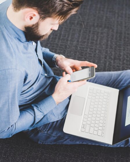 Young male sitting on office floor texting on smartphone