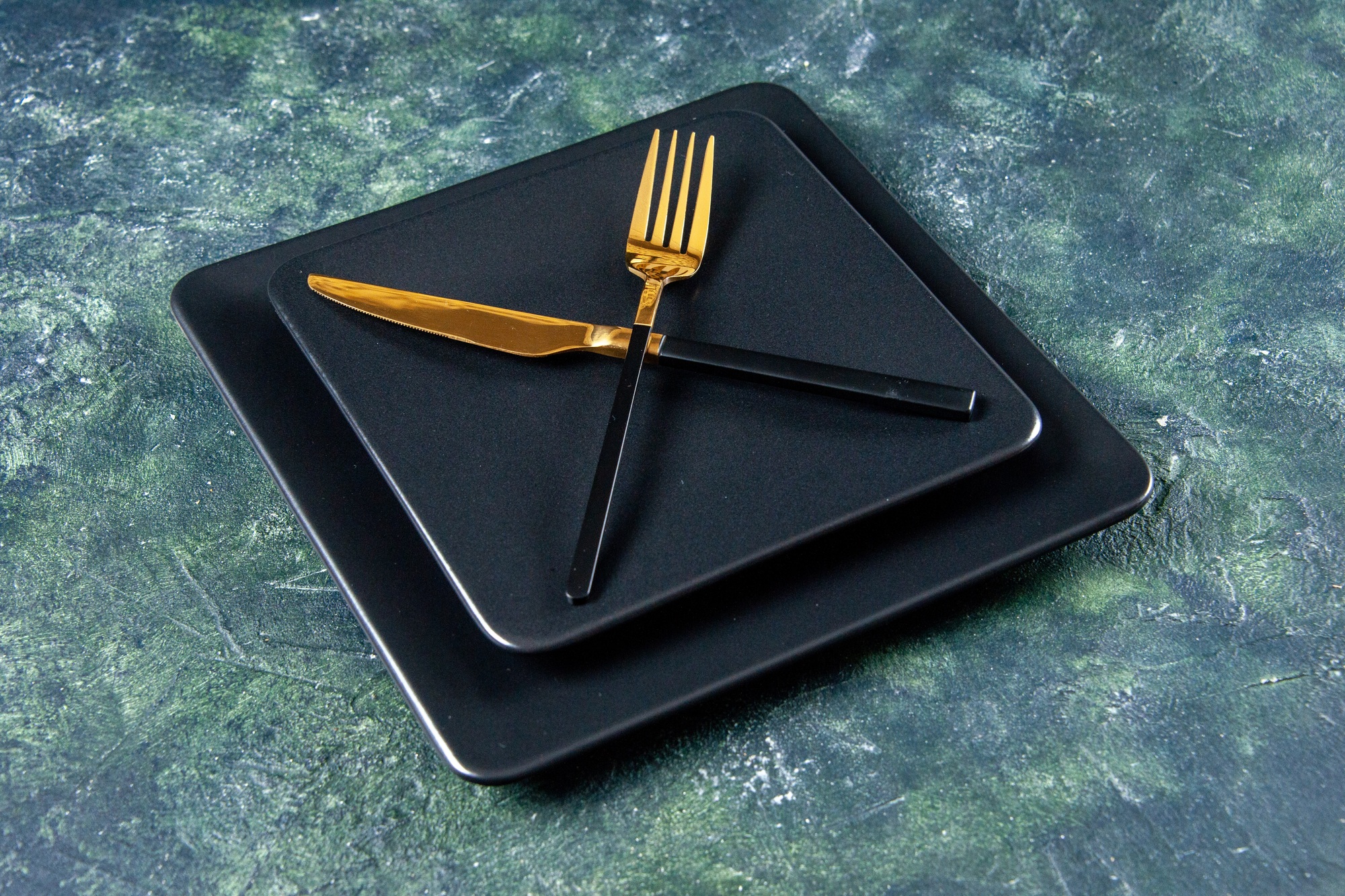 front view black plates with golden fork and knife crossed on a dark background color food cutlery