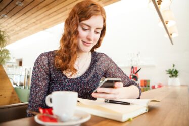 Portrait of young woman with smartphone reading SMS