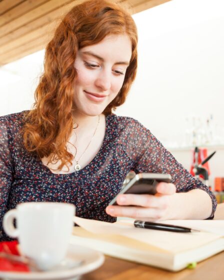 Portrait of young woman with smartphone reading SMS