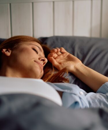 Relaxed woman enjoying in good night sleep in bedroom.